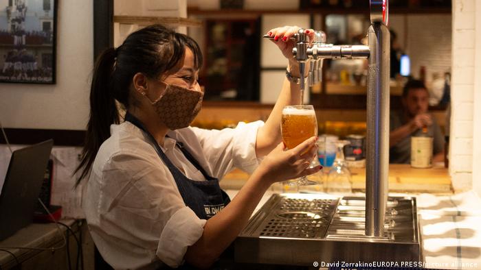 Работница ресторана наливает пиво в бокал