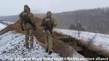 Auf diesem von der Pressestelle des ukrainischen Grenzschutzes zur Verfügung gestellte Foto beobachten ukrainische Grenzsoldaten, wie ein Spezialfahrzeug einen Graben an der ukrainisch-russischen Grenze in der Nähe von Sumy aushebt. +++ dpa-Bildfunk +++