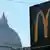Un cartel que indica la dirección de un McDonald's se ve con la cúpula de la basílica de San Pedro al fondo, cerca del Vaticano.