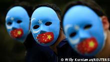 People wearing masks protest against China's treatment towards the ethnic Uyghur people and calling for a boycott of the 2022 winter Olympics in China