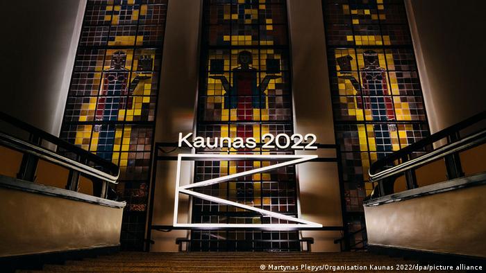 Interior view of a building and neon lights that say Kaunas 2022 