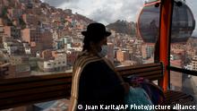 A woman wearing a mask as a precaution against the spread of the new coronavirus rides a cable car that connects the city of La Paz with El Alto, Bolivia, Thursday, May 6, 2021. (AP Photo/Juan Karita)