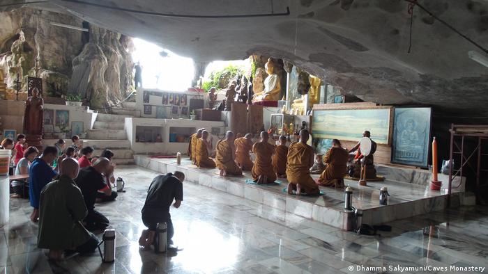 People praying in front of a gold-painted Buddha