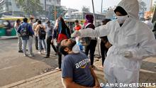 A healthcare worker wearing personal protective equipment (PPE) collects a swab sample from a man during a rapid antigen testing drive for the coronavirus disease (COVID-19) at a roadside kiosk in Ahmedabad, India, January 7, 2022. REUTERS/Amit Dave