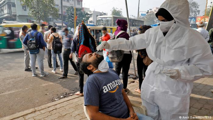 Foto seorang petugas kesehatan menggunakan baju hazmat melakukan tes usap di pinggir jalan di India