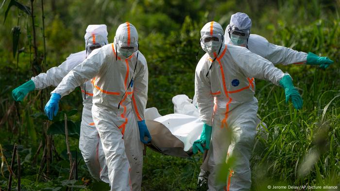 Congolese burial workers in protective gear carry the remains of an Ebola victim