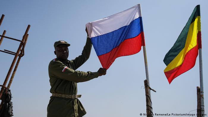 A Malian resident in Bamako poses in military garb and holds the Russian flag