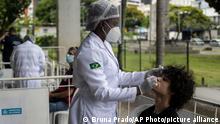 A healthcare worker takes a nasal sample for a COVID-19 test, at a test site set up at a school in Rio de Janeiro, Brazil, Friday, Jan. 7, 2022. (AP Photo/Bruna Prado)