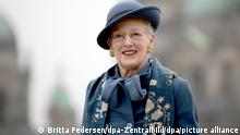 Queen Margrethe II wearing a hat and smiling.