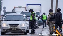 Kazakh law enforcement officers stand guard at a checkpoint on a road in Nur-Sultan