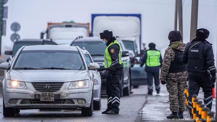 Kazakh law enforcement officers stand guard at a checkpoint on a road in Nur-Sultan