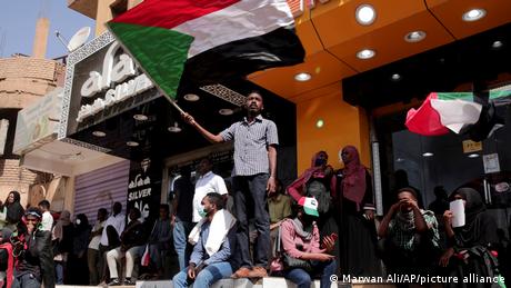 People chant slogans in Khartoum as several wave the Sudanese flag