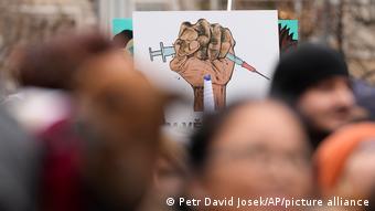 Противники вакцинации держат плакат на акции протеста в Праге