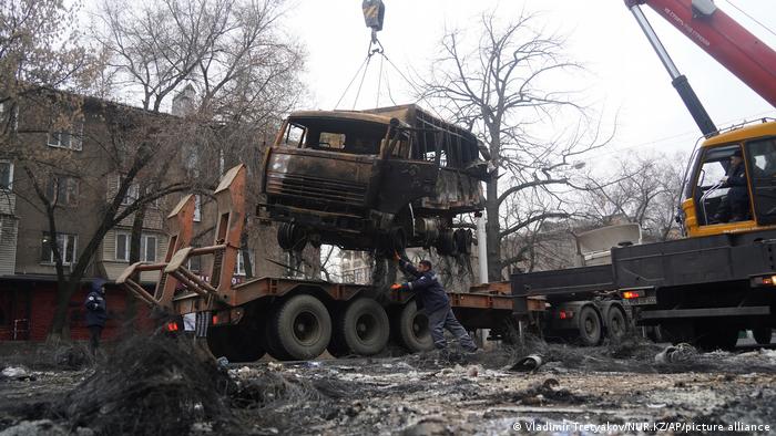 A burned out vehicle is lifted by a crane