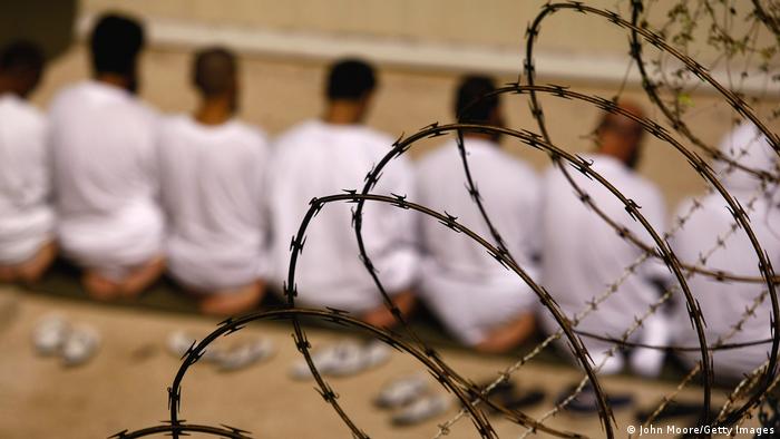 Inmates of the Guantanamo camp, praying behind barbed wire