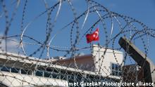 A Turkish flag behind barbed wire fence of the Silivri courthouse, in Silivri, outside Istanbul, Monday, Sept. 7, 2020, before the trial of Abdulkadir Masharipov, the main suspect in the New Year's Eve attack that left 39 people dead in Istanbul in 2017. A verdict is expected in the trial of Masharipov, who is an Uzbekistan national. (AP Photo/Mehmet Guzel)