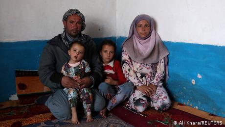 Marktträger Sayed Yassin Mosawi, 31 sitzt mit seiner Frau und den beiden Kleinkindern in seiner kargen Hütte in Bamiyan, Afghanistan. 22. Dezember 2021.