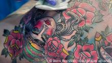 Überschüssige Farben entfernt eine Tätowiererin am 21.03.2015 auf der International Tattoo-Convention in Frankfurt am Main (Hessen) von der Brust eines Kunden. Tattoo-Künstler aus der ganzen Welt zeigten auf den verschiedenen Ständen ihr Können. Besucher konnten sich vor Ort ihr eigenes Wunsch-Motiv unter die Haut stechen lassen. Foto: Boris Roessler/dpa ++ +++ dpa-Bildfunk +++