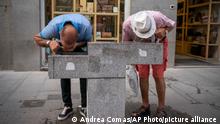 Two man drink water from a fountain during a heatwave in Madrid, Spain, Saturday, Aug. 14, 2021. Temperatures were set to hit a maximum of 46 degrees Celsius in Spain on Saturday, as the country sweltered on the hottest day of the year so far. (AP Photo/Andrea Comas)