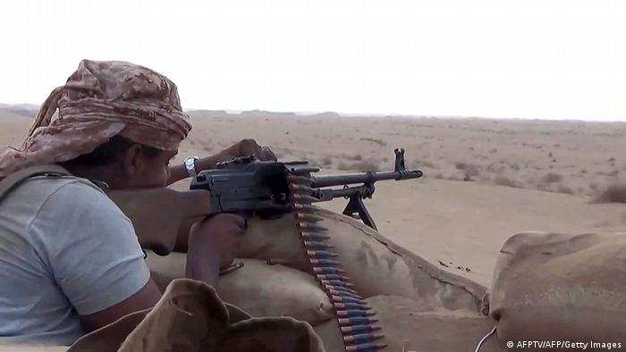 Ein Mann läd hinter einem Wall aus Sandsäcken in einer Wüstenlandschaft der Schabwat-Provinz im Jemen sein Maschinengewehr nach 