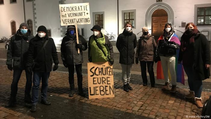 ocho manifestantes con eslóganes en pancartas a favor de la democracia y las restricciones pro-COVID