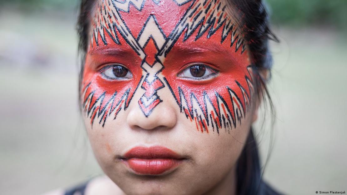 Mulher indígena com rosto pintado de preto e vermelho