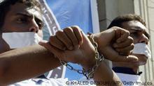 CAIRO, EGYPT: Some 3,000 members of the Muslim Brotherhood movement protest with their wrists symbolically chained at the campus of Cairo University 11 October 2005 to press for increased freedom on campus and free and fair union elections next month. The area was circled by hundreds of riot police to prevent the protesters, including students from other universities outside Cairo, from venturing onto the streets. Various reports have documented widespread infringements on freedom of expression in Egyptian universities. But while Islamists have been the target of crackdowns by state security, they have themselves been accused of seeking to restrict freedoms and imposing Islamic values on students, especially women. AFP PHOTO/KHALED DESOUKI (Photo credit should read KHALED DESOUKI/AFP via Getty Images)