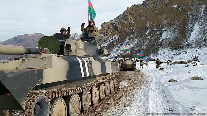 Azerbaijani soldiers with a flag sitting atop a tank