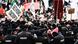 Black-clad police in the foreground of a thick crowd of banner-waving protesters Black-clad police in the foreground of a thick crowd of banner-waving protesters