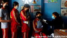 Students wait in a queue as their friend receives a dose of the Moderna vaccine against the coronavirus disease (COVID-19), at their school during a vaccination drive for children aged 12-17 in Bhaktapur, Nepal, January 9, 2022. REUTERS/Navesh Chitrakar 