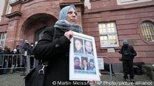 Syrian woman Yasmen Almashan holds the pictures of her five in Syria died brothers before the verdict in front of the court in Koblenz, Germany, Thursday, Jan. 13, 2022. The German court has convicted a former Syrian secret police officer of crimes against humanity for overseeing the abuse of detainees at a jail near Damascus a decade ago. (AP Photo/Martin Meissner)
