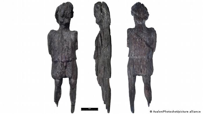 Vorder-, Rücken- und Seitenansicht einer antiken Holzfigur, die vernutlich eine Tunika trägt