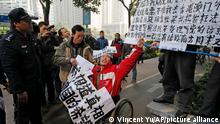 FILE - In this Jan. 10, 2013 file photo, a policeman stands near a supporter, center in wheelchair, of the Southern Weekly during a protest before being taken away by police near the Southern Weekly headquarters in Guangzhou, Guangdong province, China. A court sentenced Chinese activist Yang Maodong - better known by his penname Guo Feixiong - to six years in prison Friday, Nov. 27, 2015, in what his lawyer described as an unfair trial with an extra criminal charge added at the last minute. Yang helped organize demonstrations and spoke in support of the editorial staff at Southern Weekly after its journalists complained of censorship. (AP Photo/Vincent Yu, File)