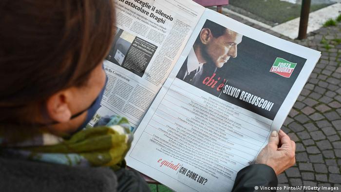 A woman reads a full-page ad of Berlusconi's campaign for the upcoming presidential election