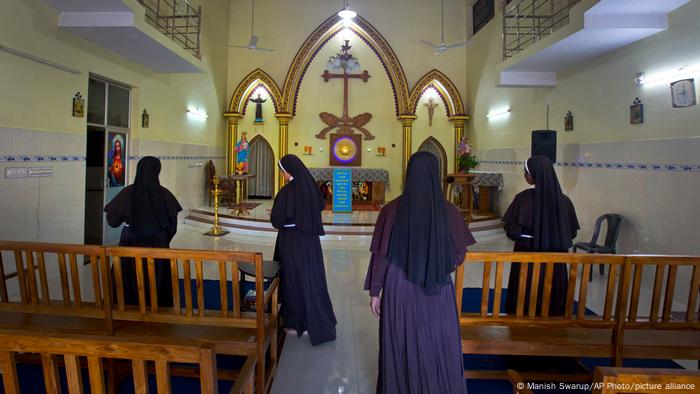 The backs of nuns inside a chapel wearing blue gowns The backs of nuns inside a chapel wearing blue gowns