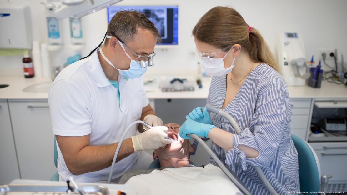 Dos dentistas, un hombre y una mujer, realizan un tratamiento dental a un hombre. Dos dentistas, un hombre y una mujer, realizan un tratamiento dental a un hombre.