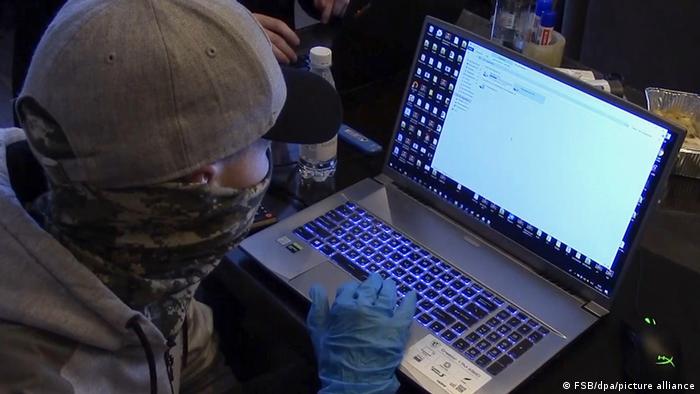A Russian security agent checking the laptop of a detained hacker before the invasion