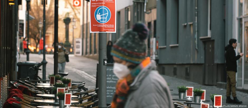 A woman walks pass a cafe with empty chairs and tables in city center of Bonn, Germany