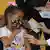 Menina com mácara com motivos infantis recebe a vacina de uma profissional da saúde. 