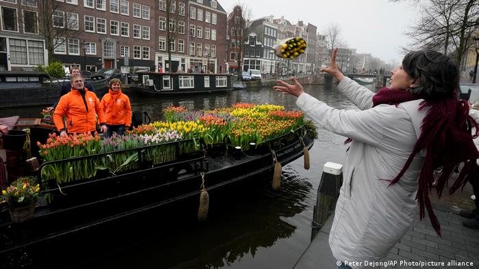 Una mujer atrapa un ramo de tulipanes en Ámsterdam, durante una acción iniciada por algunos comerciantes que pudieron reabrir lentamente sus negocios luego de semanas de cierre por el aumento de contagios de coronavirus.