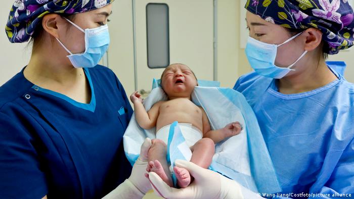 Medical staff wearing face masks hold a newborn in a delivery room in Zhangye City, Gansu Province, China, May 26, 2021