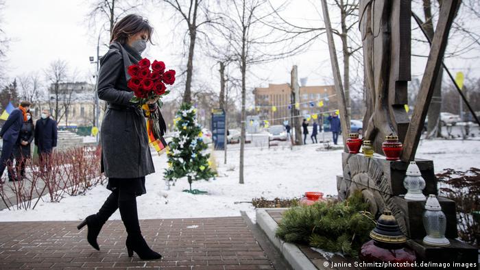Annalena Baerbock geht mit einem Strauß roter Rosen mit einer schwarz-rot-goldenen Schleife auf das Denkmal der Himmlischen Hundertschaft zu