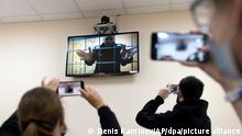 Alexej Nawalny (oben, Monitor), Oppositionspolitiker aus Russland, wird von Journalisten gefilmt, während er über eine Videoverbindung der Strafvollzugsbehörde, an einer Gerichtsverhandlung teilnimmt. Der seit einem Jahr inhaftierte Nawalny spricht per Videolink vor einem Gericht zur Anhörung seiner Klage gegen seine Gefängniskolonie, die ihn als potenzielle extremistische oder terroristische Bedrohung einstuft. +++ dpa-Bildfunk +++