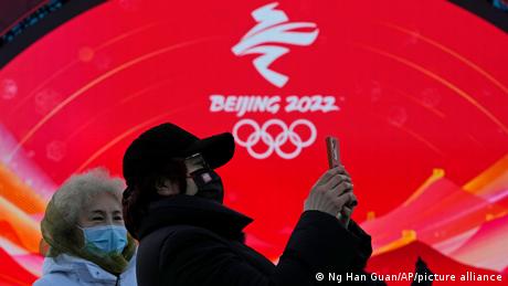 Жінки з телефоном на тлі символу Олімпіади в Пекіні-2022