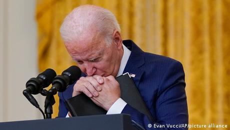 US-Präsident Joe Biden verschränkt seine Hände und stützt seinen Kopf darauf, sein Blick ist gesenkt