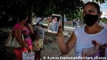 Yaquelin Cruz show a photo of her son Dariel Cruz, who was arrested during the July 11 protests, in front of the court building where he is being tried in Havana, Cuba, Tuesday, Jan. 11, 2022. Six months after surprising protests against the Cuban government, more than 50 protesters who have been charged with sedition are headed to trial and could face sentences of up to 30 years in prison. (AP Photo/Ramon Espinosa)