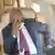Alpha Condé dans un avion, portant un masque sanitaire et se tenant la tête (Photo d'illustration)