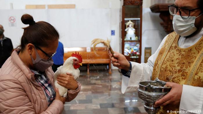 Eine Frau mit ihrem Huhn in der Kirche am Tag des Heiligen Antonius