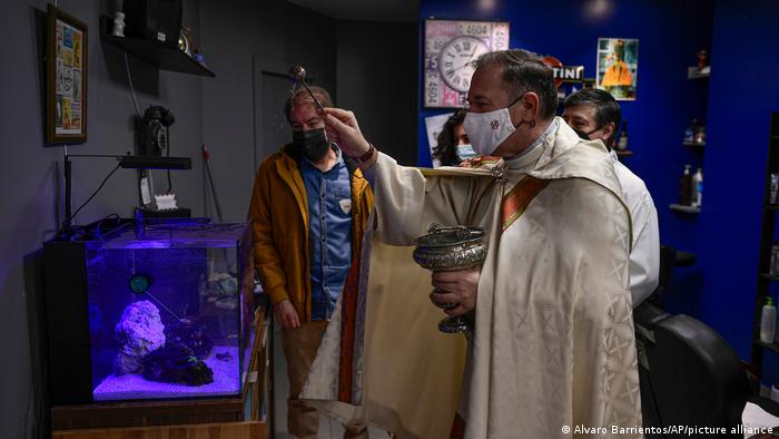 Father Cesar Magana blesses an acquarium filled with fish. 