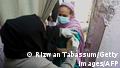 Health worker inoculates woman with PakVac during door-to-door vaccination in Karachi